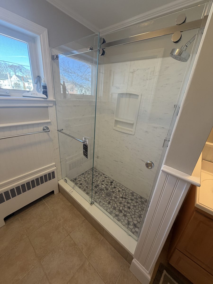 semi-frameless sliding bypass shower door chrome hardware pebble floor tile Peabody MA home